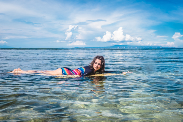 ヌサドゥア ビーチ、バリ、インドネシアの海のサーフィン ボードにウェット スーツの若いスポーツ選手の側面図 - 写真・画像