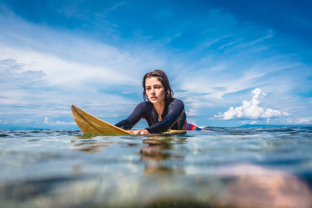 portrait of young sportswoman in wetsuit on surfing board in ocean at Nusa dua Beach, Bali, Indonesia - Photo, Image