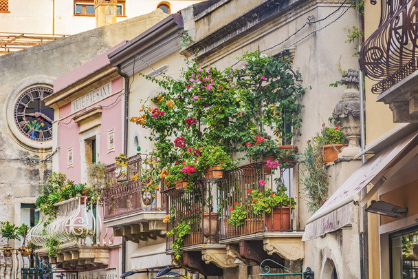 balcón con macetas rojas y follaje verde en Toarmina, Sicilia, Italia
 - Foto, Imagen