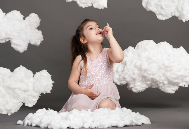 fille jouant avec les nuages, tourné dans le studio sur un fond gris
 - Photo, image