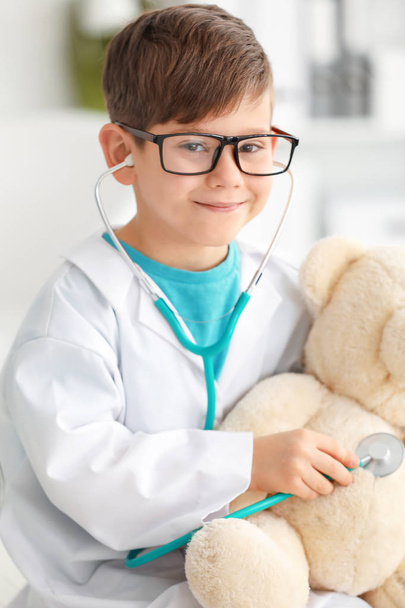 niño en ropa de médico jugando con oso de juguete en el hospital
 - Foto, imagen
