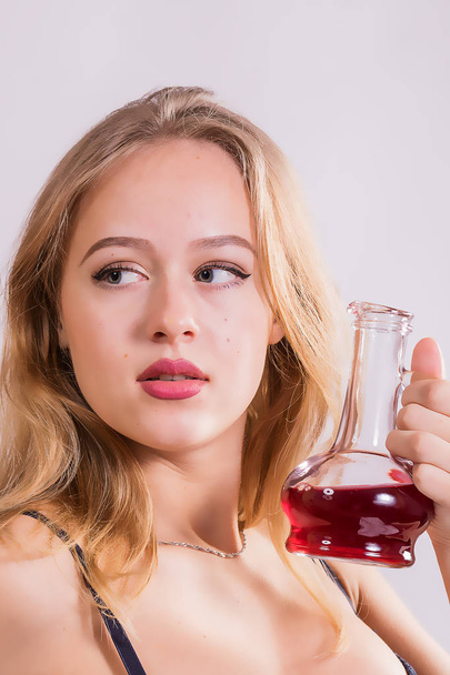 A young girl and a vessel of red liquid. - Foto, afbeelding