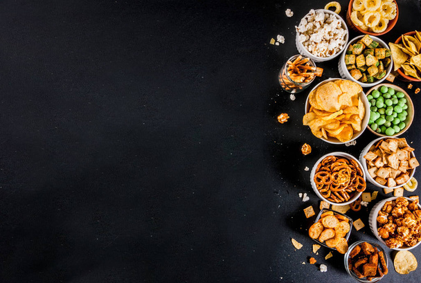 Varyasyon farklı sağlıksız atıştırmalıklar kraker, tatlı tuzlu popcorn, ekmeği, fındık, payet, bretsels, arka kara tahta kopya alanı - Fotoğraf, Görsel