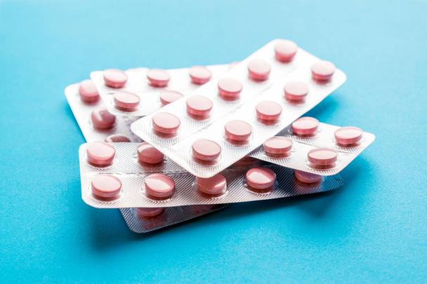 Detailní záběr růžové tablety ve stříbrné v blistru na modrém pozadí. Léky na předpis nepoužitá. Není bezpečné vzít neplatné léky. Selektivní fokus - Fotografie, Obrázek