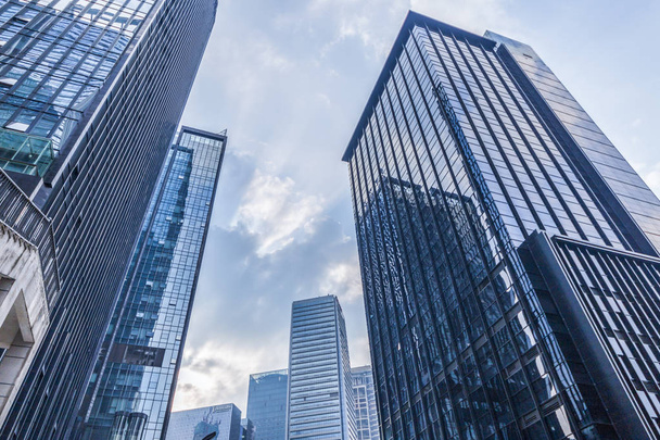 Нижний вид на современные небоскребы в деловом районе против голубого неба - Фото, изображение