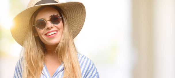 Güneş gözlüğü ve kendinden emin ve mutlu bir büyük doğal gülümseme gülmek ile yaz şapka giyen genç kadın - Fotoğraf, Görsel