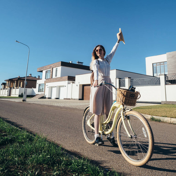Bella ragazza in cappello e vestito da incrociatore in bicicletta in periferia
. - Foto, immagini