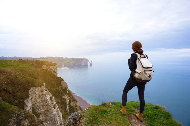 beautiful landscape, girl standing at the edge of rock in the Etretat. Franc - Фото, изображение