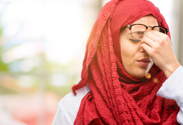 Nuori arabinainen yllään hijab unelias ilme, ylityöllistetty ja väsynyt, rubbes nenä, koska väsymys
 - Valokuva, kuva