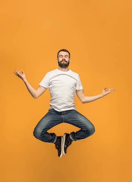 Freedom in moving. handsome young man jumping against orange background - Foto, Bild