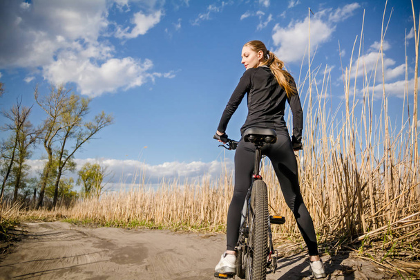 Fiatal nő a kerékpár út a természet háttérben állva - Fotó, kép