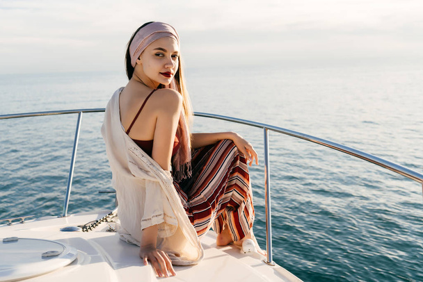 a luxurious rich woman sits on her white yacht, sails across the Caribbean and smiles - Фото, изображение