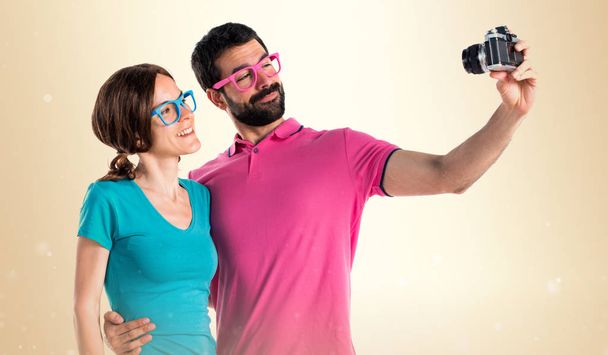 Casal em roupas coloridas fazendo uma selfie
 - Foto, Imagem