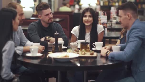 Freunde lachen und amüsieren sich an einem Tisch in einem Restaurant. eine Gruppe von Freunden verbringt Zeit miteinander und genießt die Geselligkeit. - Filmmaterial, Video