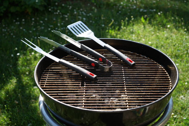 Cutlery for sausages barbecue with a charcoal barbecue in the garden - Foto, imagen