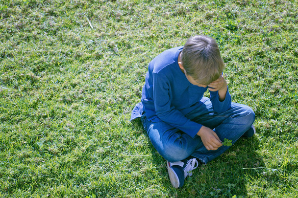 Malheureux triste garçon bouleversé assis seul sur l'herbe
 - Photo, image