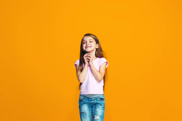 The happy teen girl standing and smiling against orange background. - Foto, Bild