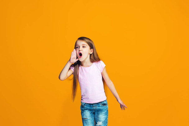 Isolated on orange young casual teen girl shouting at studio - Фото, изображение