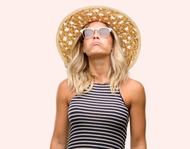 Fiatal nő segítségével napszemüveg viselése nyári kalap álmos kifejezés, hogy túlterheltek, és fáradt - Fotó, kép