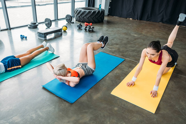 çok kültürlü kadın sporcular spor salonunda fitness paspaslar üzerinde egzersiz  - Fotoğraf, Görsel