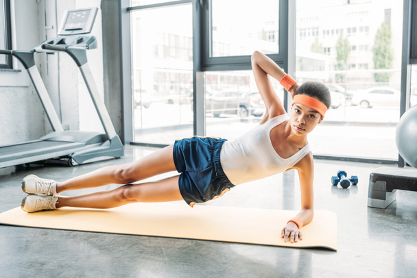 african american sportswoman doing side plank of fitness mat at gym - Fotografie, Obrázek