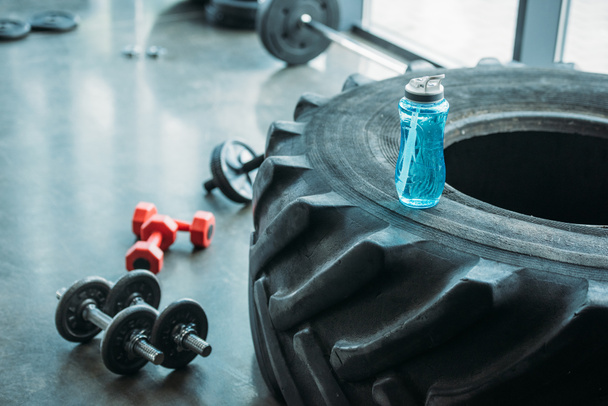 vue rapprochée de différents haltères, rouleau abs et bouteille d'eau sur le pneu d'entraînement à la salle de gym
 - Photo, image