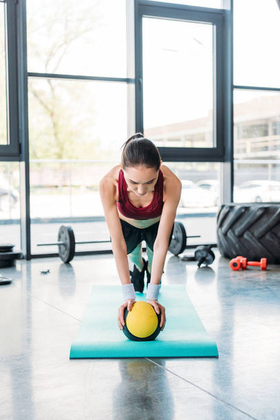 young asian sportswoman balancing on ball on fitness mat at gym - Foto, Imagem