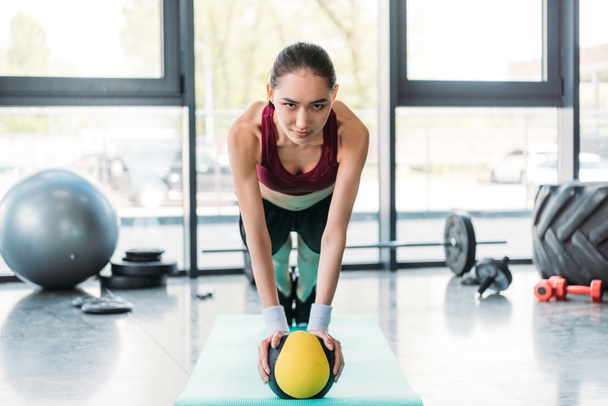 young asian sportswoman balancing on ball on fitness mat at gym - Photo, image