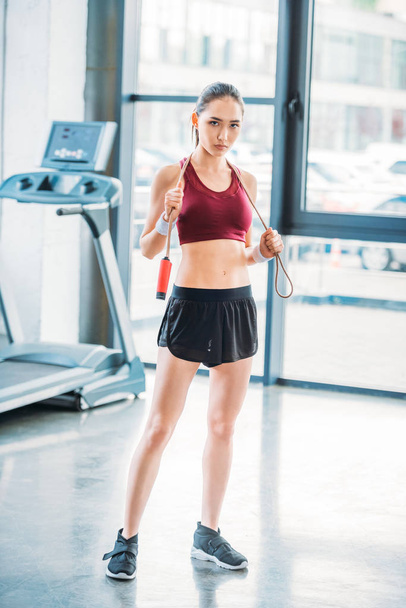 young asian sportswoman with skipping rope looking at camera at gym - Фото, зображення