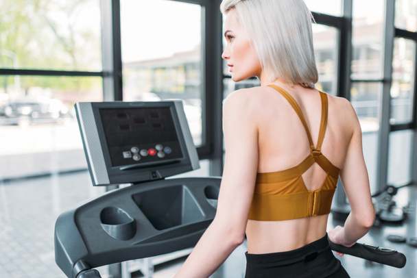 back view of young sportswoman training on treadmill at gym - Фото, зображення