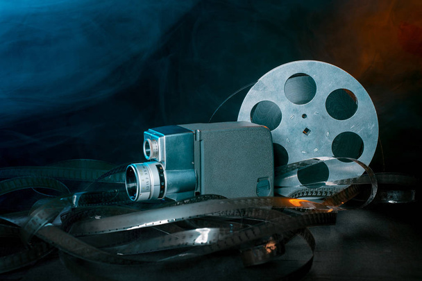 Câmera de filme de 8 mm com um movimento cambaleante de filme na fumaça. fundo escuro
 - Foto, Imagem