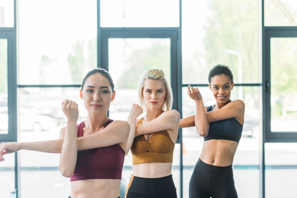 portrait of attractive multiracial sportswomen stretching before working out at gym - Foto, immagini