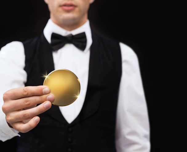 primer plano del distribuidor del casino que sostiene la moneda de oro
 - Foto, Imagen