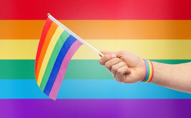 hand with gay pride rainbow flag and wristband - Foto, afbeelding