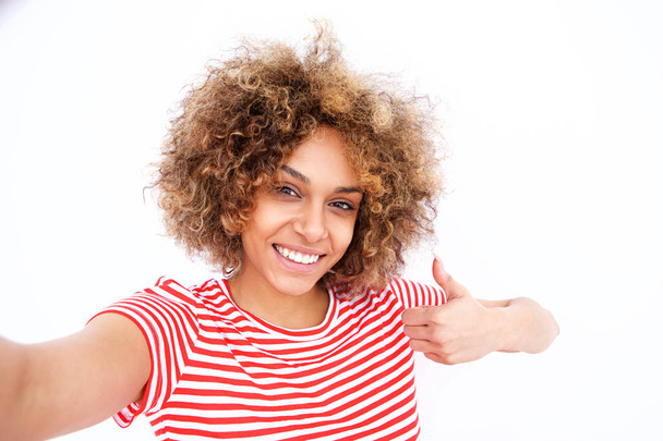 Portrait de jeune femme afro-américaine confiante prenant selfie avec les pouces vers le haut sur fond blanc
 - Photo, image