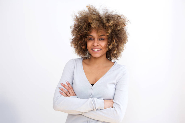 Retrato de una joven afroamericana confiada sonriendo sobre fondo blanco con los brazos cruzados
 - Foto, imagen