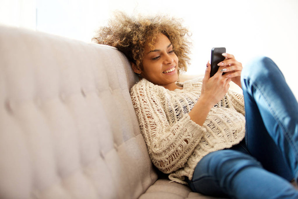 自宅で座って携帯電話を見て流行の若い女性の肖像画 - 写真・画像