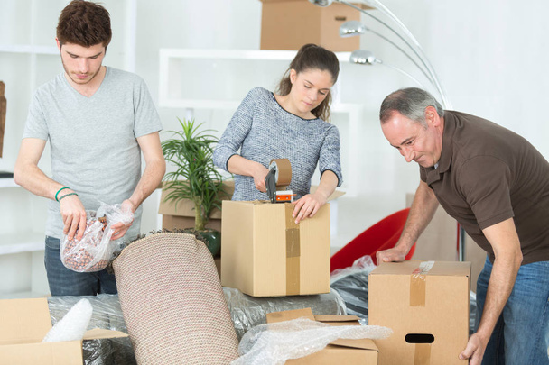 family unpacking cardboard boxes at new home - Foto, imagen