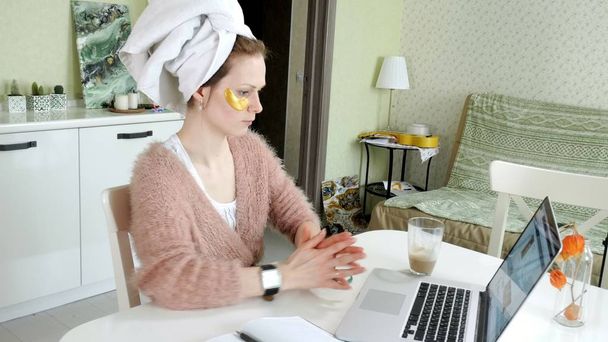 houkutteleva liike nainen soveltamalla kosmeettisia kasvojen täpliä kotona, työskentelee kannettavan tietokoneen takana
 - Valokuva, kuva