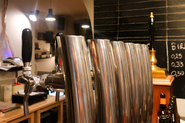 Rubinetti di birra in argento con manici neri e bellissimi riflessi in una birreria artigianale con una lavagna nera con spazio vuoto durante la sera
 - Foto, immagini