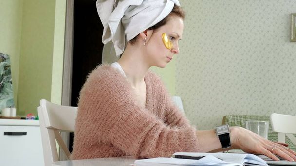 ελκυστική γυναίκα εφαρμογή καλλυντικών προσώπου κηλίδες στο σπίτι, εργάζονται πίσω από το laptop - Φωτογραφία, εικόνα