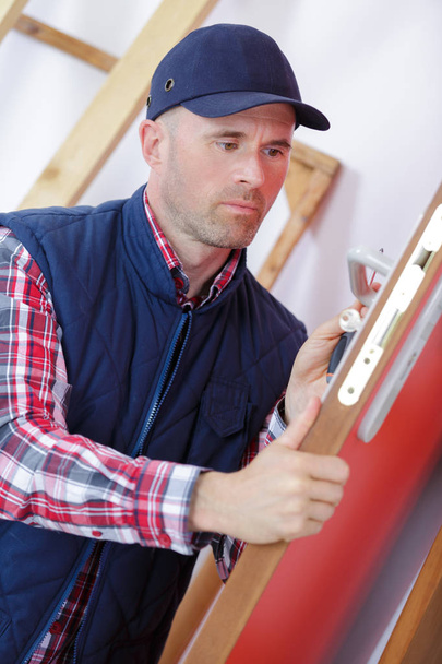 male carpenter worker at interior wood door lock installation - Fotó, kép