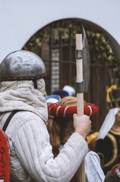 Actors wearing medieval costumes, one of them standing with sword during festival - Foto, afbeelding