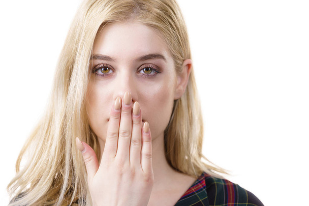 Primo piano della giovane donna bionda che mostra il gesto del silenzio nascondendo la bocca essendo le mani. - Foto, immagini