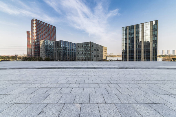Panoramatické panorama a moderní kancelářské budovy s prázdnou silnicí, prázdné betonové čtvercové podlahy - Fotografie, Obrázek