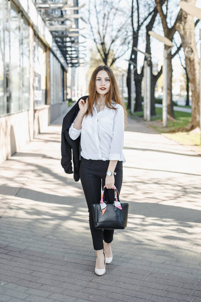 A business woman goes down the street. A girl in a business suit at the office. A wonderful girl in the city. - Фото, зображення