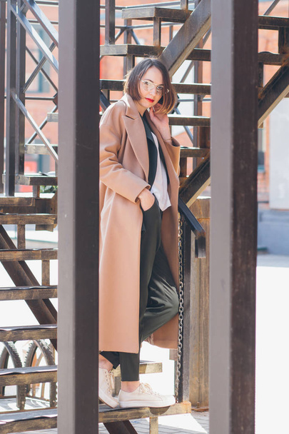 Young beautiful woman in a business suit and coat posing on the streets. Toning. - Photo, Image