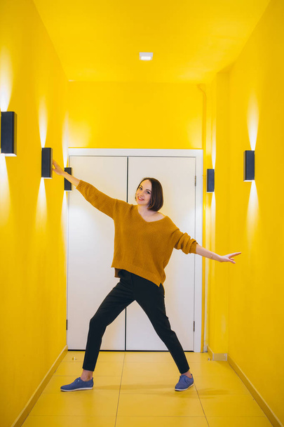 Young beautiful woman posing against the yellow wall. Toning. - Foto, imagen