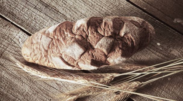 Freshly baked traditional bread on wooden table - Фото, зображення