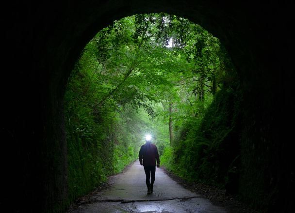 Randonneur illuminant le chemin en entrant dans un tunnel
. - Photo, image
